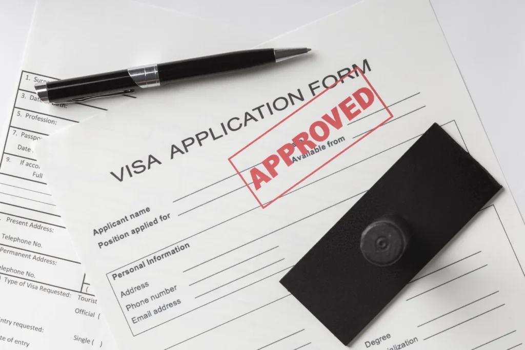 Visa application documents and a passport laid out on a desk for an E-2 visa filing