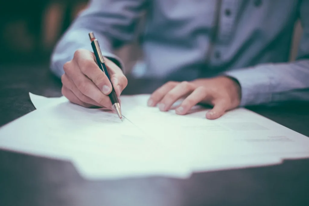 Person signing an application form, illustrating Form I-485 and the adjustment of status process