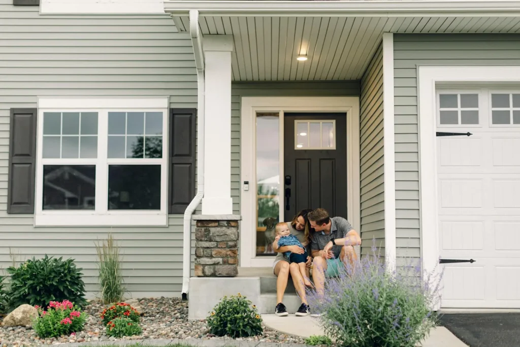 Family sitting in front of their home, illustrating a living trust vs will decision in Florida